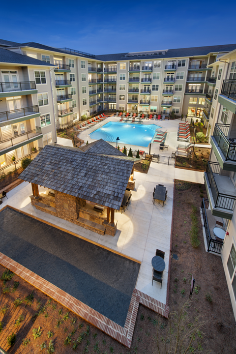 Aerial view of the swimming pool, grilling area, and top of the apartment roofs.